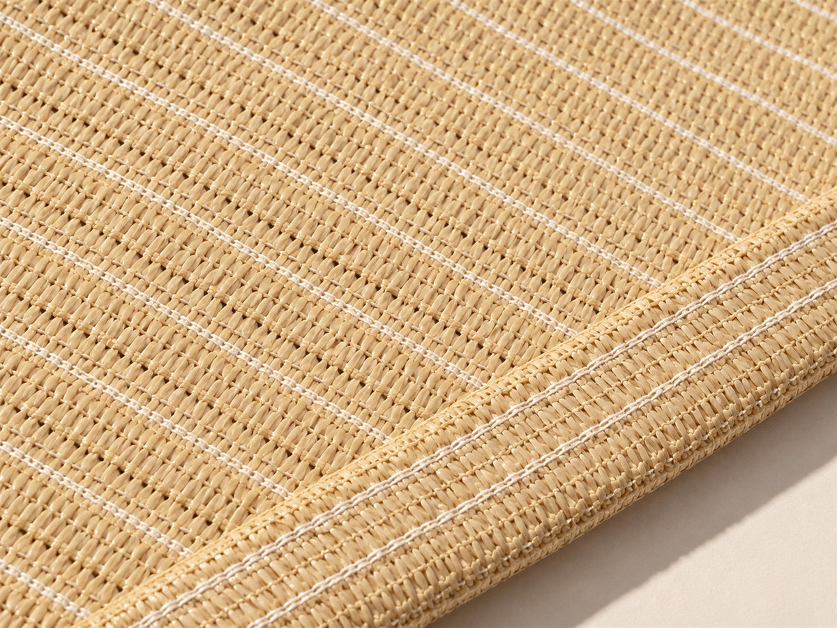 Close-up of beige knitted shade fabric and its stitched reinforced edge.